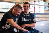Tim Tszyu rubs the head of his father, Kostya, while sitting on he edge of a boxing ring.