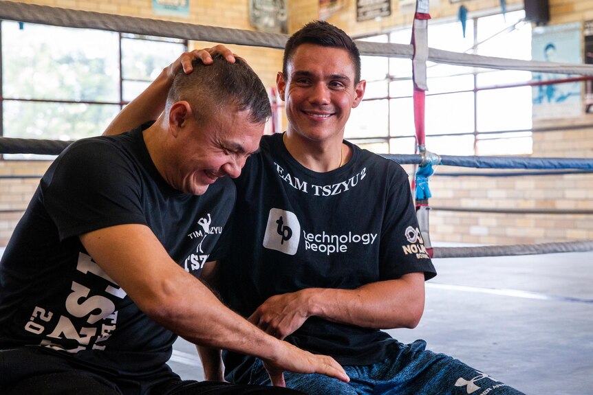 Tim Tszyu rubs the head of his father, Kostya, while sitting on he edge of a boxing ring.