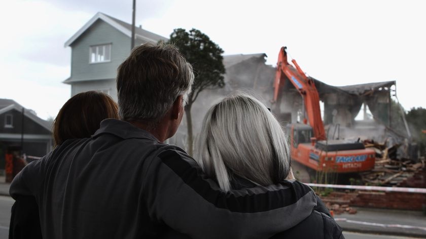 A family looks on as their quake-damaged Christchurch home is demolished