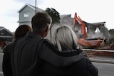 A family looks on as their quake-damaged Christchurch home is demolished