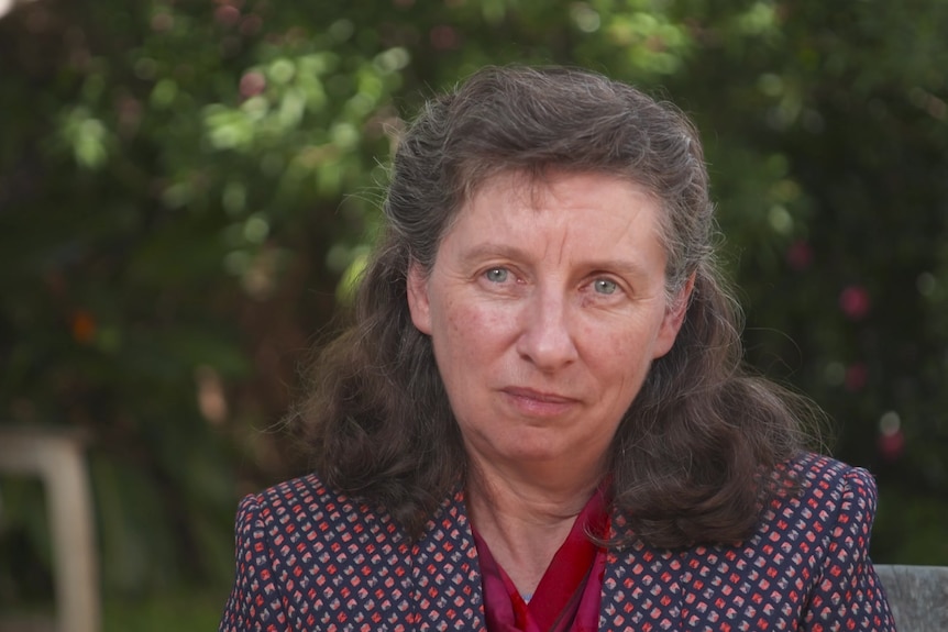 Woman wearing printed red, pink and purple blazer looking at the camera.