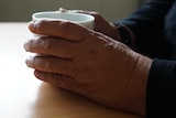 A woman's hands hold a cup of tea on a table