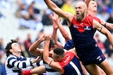 Max Gawn flies to punch a ball in front of a pack of Melbourne and Geelong players