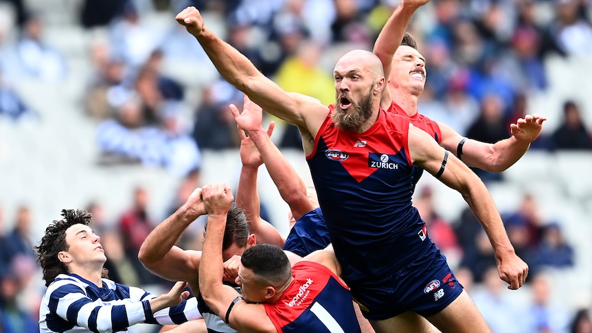 Max Gawn flies to punch a ball in front of a pack of Melbourne and Geelong players
