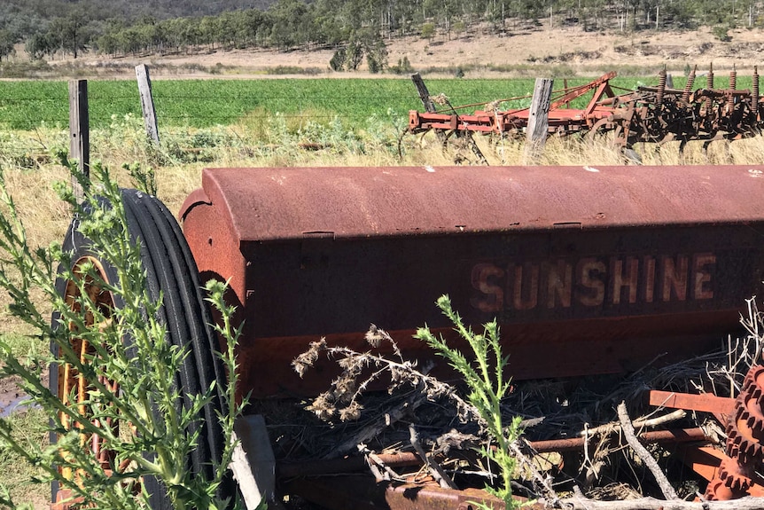 A close-up photo of Max Hockey's Sunshine harvester, in front of a background of green fields.