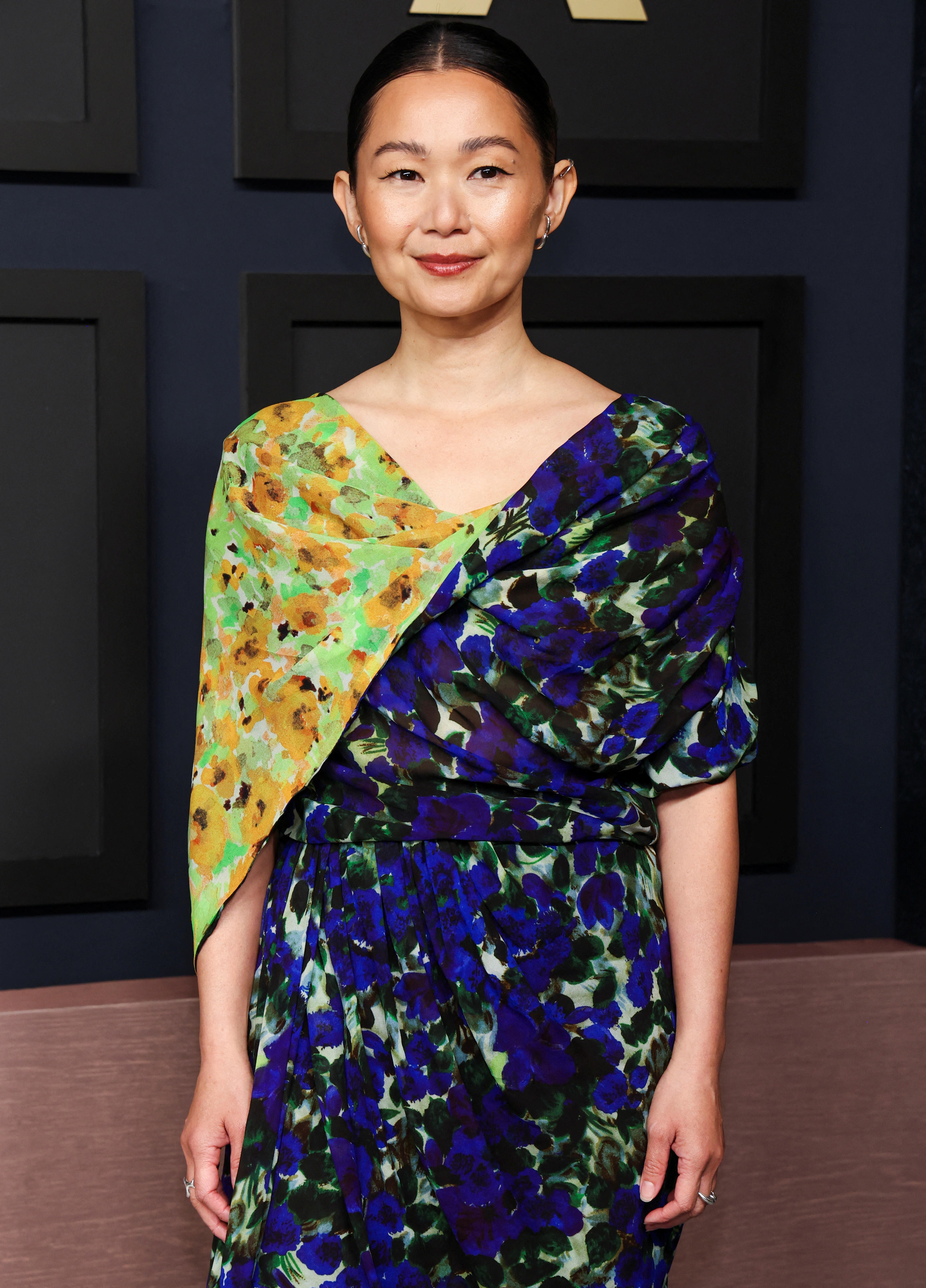 Hong Chau in a green and blue floral wrap dress on the red carpet. 