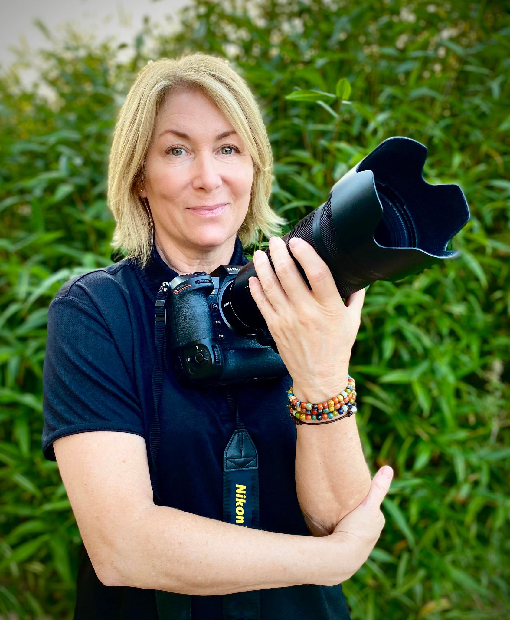 blonde woman holding a large camera and lens