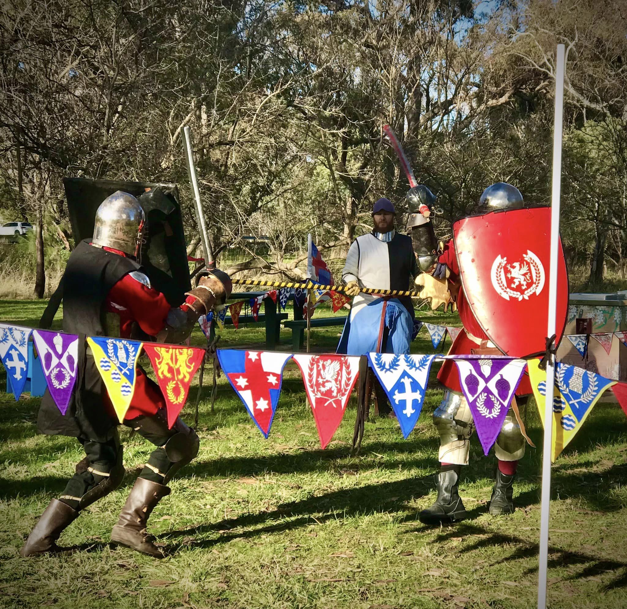 Two re-enactors in medieval armour fighting.