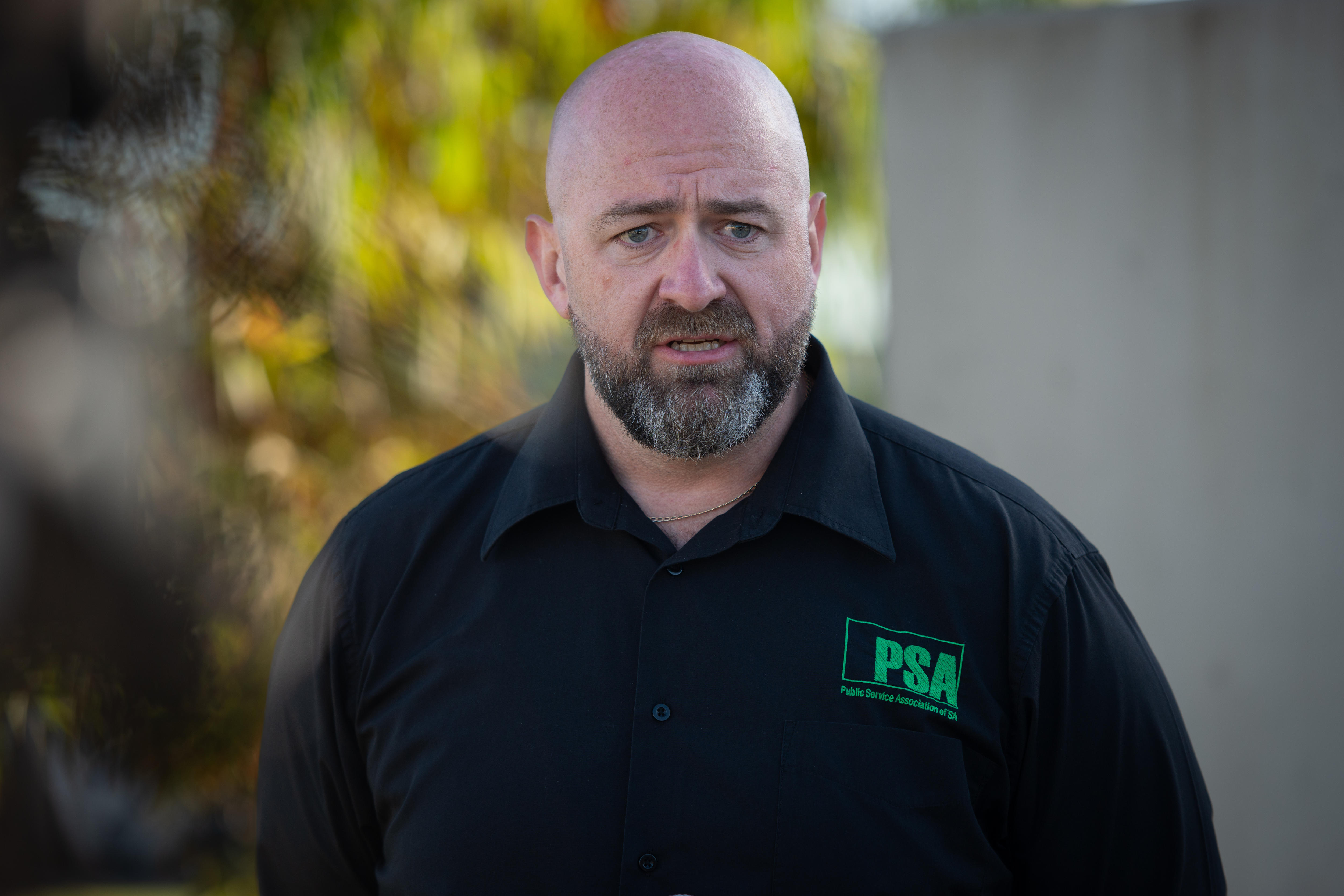 Un hombre con barba y polo negro parece preocupado.