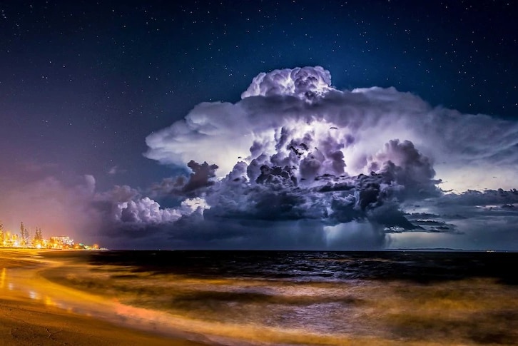 Lightning illuminates a cloud at night as a storm moves out to sea.