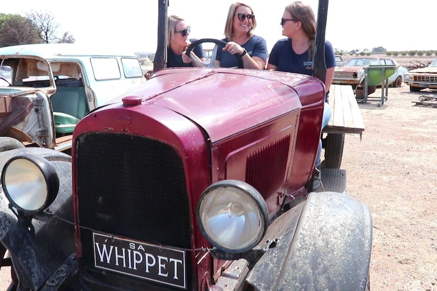 Three women seated on open air antique truck