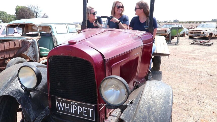 Three women seated on open air antique truck