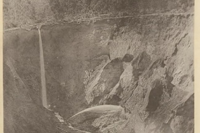 A sepia photo showing a wall of rock that has been subjected to a mining technique.