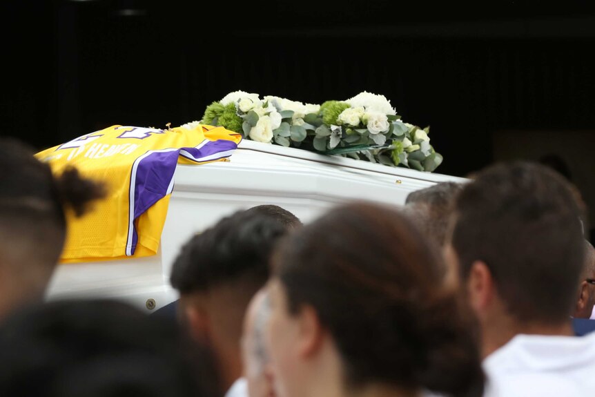 A coffin is draped in a bright jersey