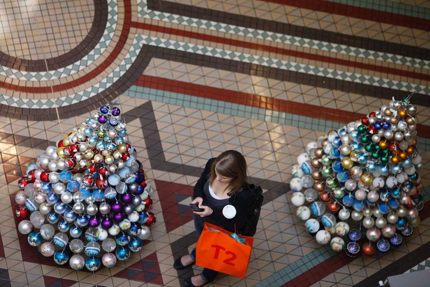 A shopper stands next to Christmas trees