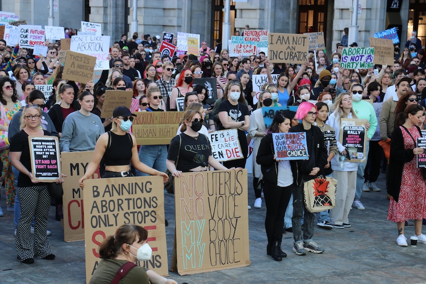 A crowd of protesters holding up various signs 