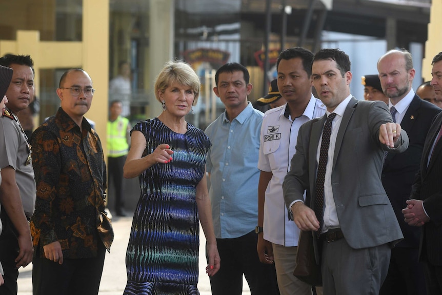 Julie Bishop points as she stands with officials.