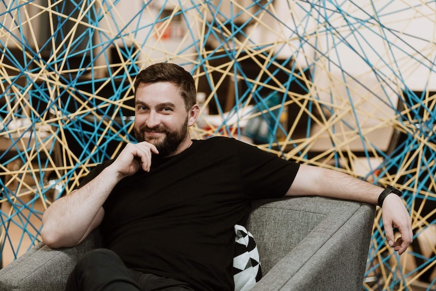 a man in a black shirt sitting comfortably and lounging back in a chair