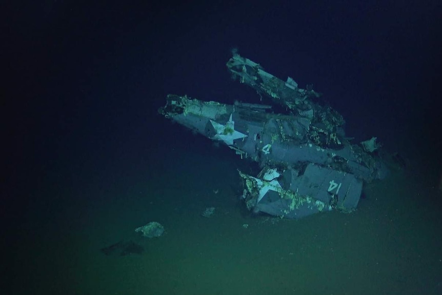 An F4F-4 Wildcat with wings folded at the wreckage of the USS Hornet.