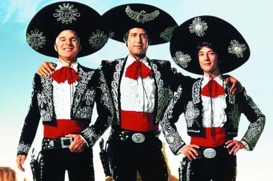 Three men wearing Mariachi costumes face the camera.