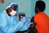 Health worker injects woman with Ebola vaccine