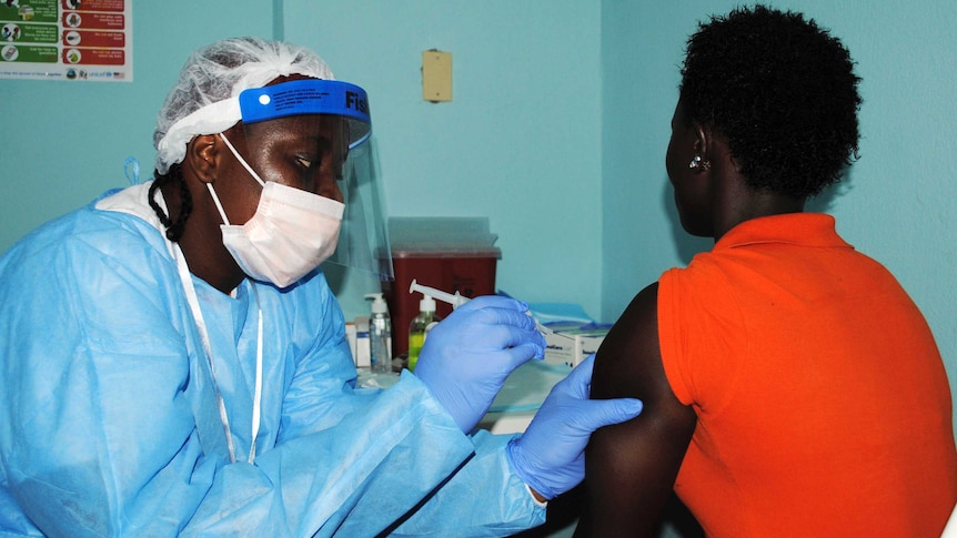 Health worker injects woman with Ebola vaccine during trial in Monrovia