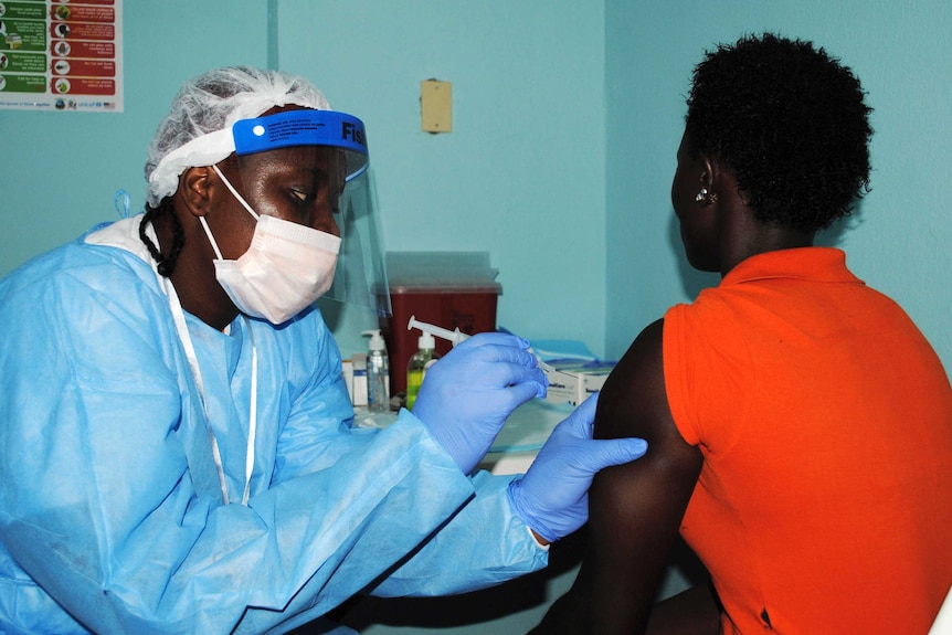 Health worker injects woman with Ebola vaccine during trial in Monrovia