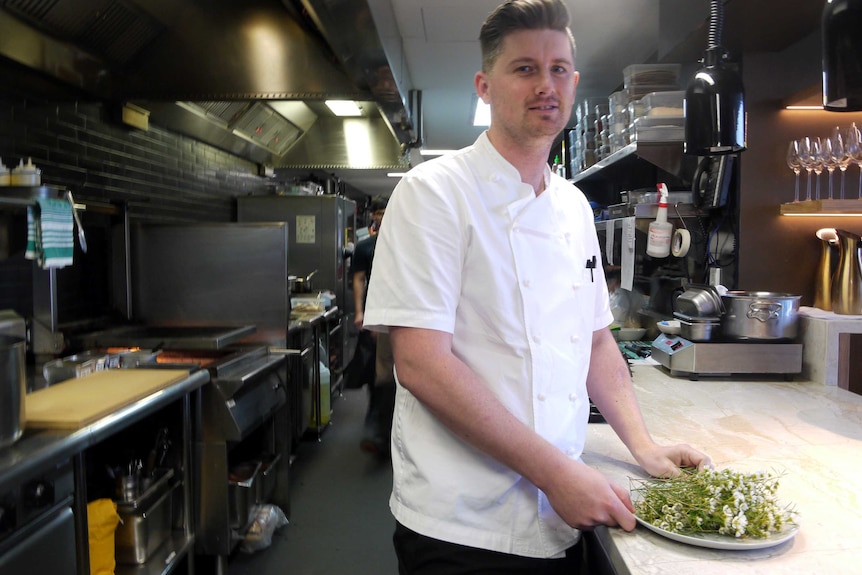 Jed Gerrard in the kitchen of Wildflower restaurant with a plate of Geraldton wax.