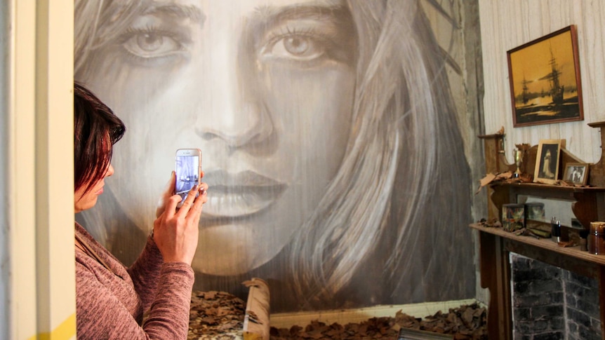 Woman takes a photo of mural