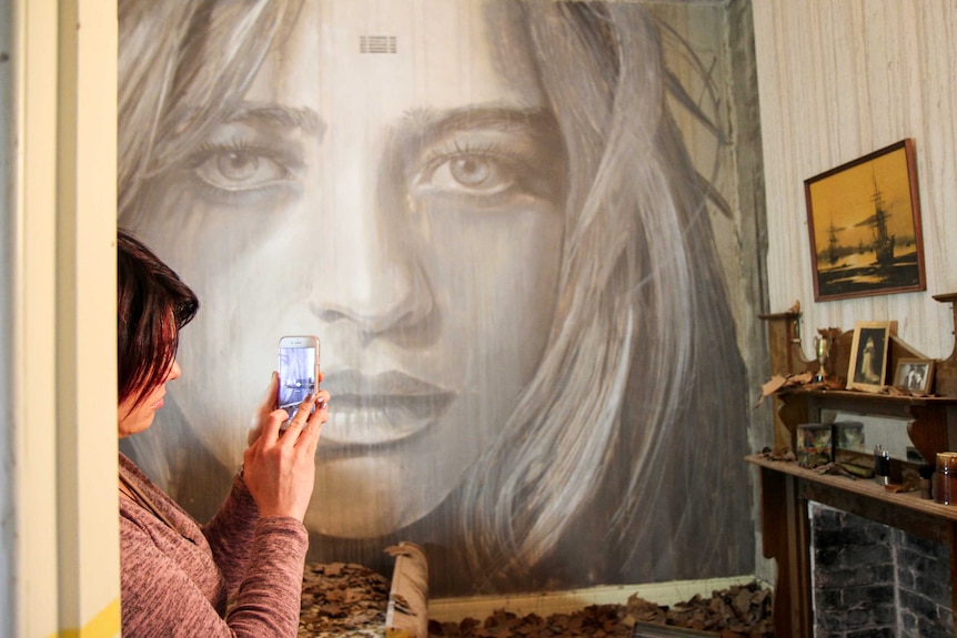 Woman takes a photo of mural