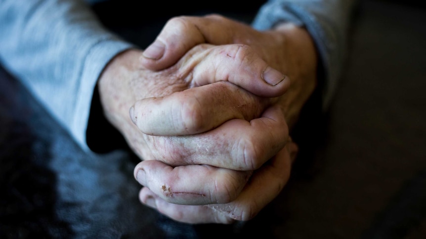 Generic older woman's worn hands clasped