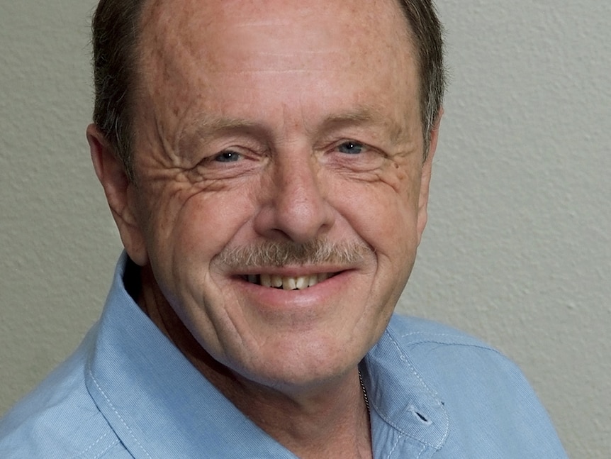 A headshot of a middle-aged man with dark hair.