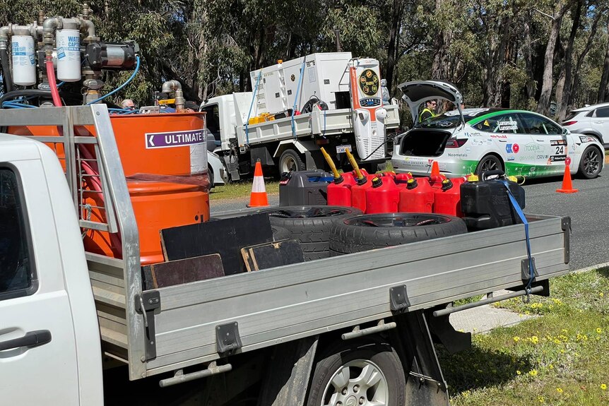 A ute with jerry cans of petrol and an EV charging in the background