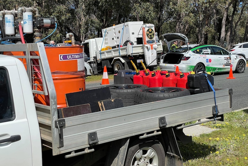 A ute with jerry cans of petrol and an EV charging in the background