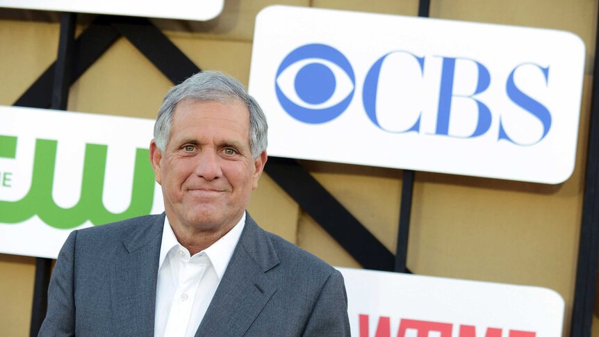 Sacked CBS executive Les Moonves stands in front of a logo wall with the CBS logo in the top-right corner