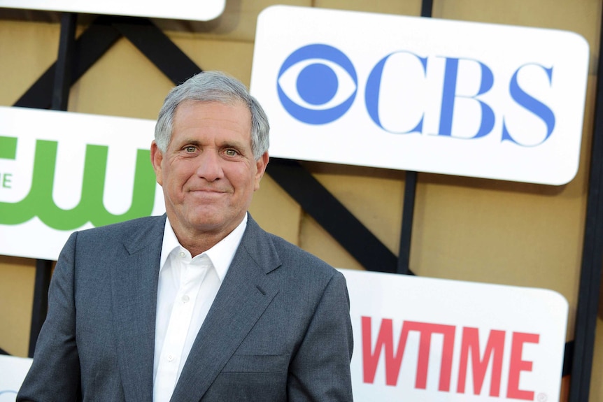 Sacked CBS executive Les Moonves stands in front of a logo wall with the CBS logo in the top-right corner