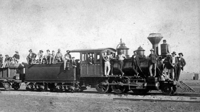 Black and white photo of a pioneer train with men standing on it.