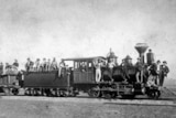 Black and white photo of a pioneer train with men standing on it.
