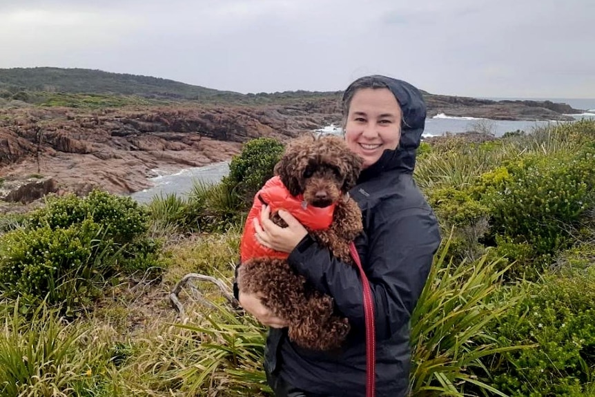 Lady holding dog with rain jacket on