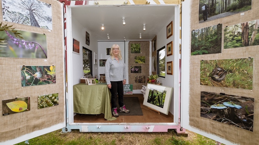 Woman standing in shipping container amongst artworks