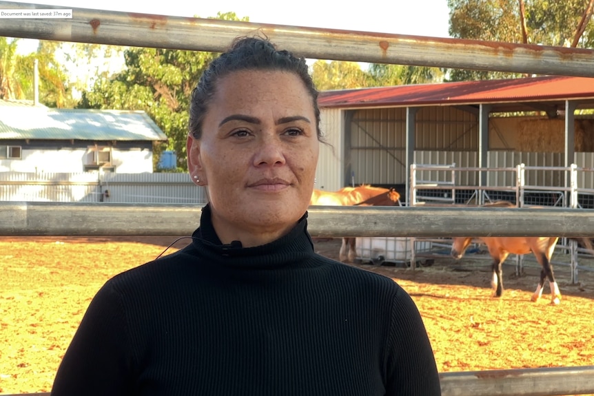 A women wit black hair in a black top standing on red dirt 