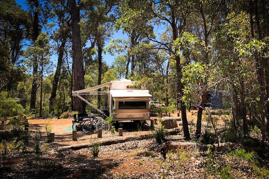 A wind-up caravan with bikes out front set up in a remote bush setting