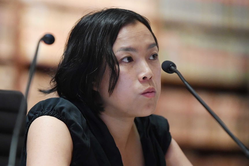 A woman with black hair in front of a microphone