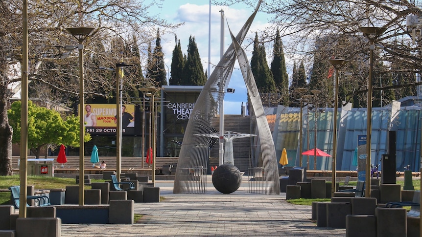 A tall metal statue stands in the middle of a path.