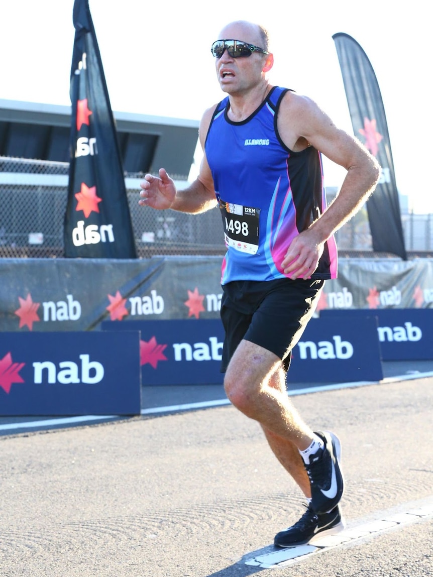 A man in a running outfit runs along a track