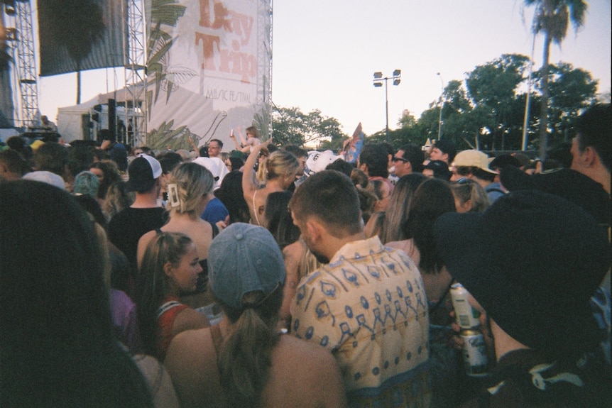 Crowds of people stand in front of an outdoor stage