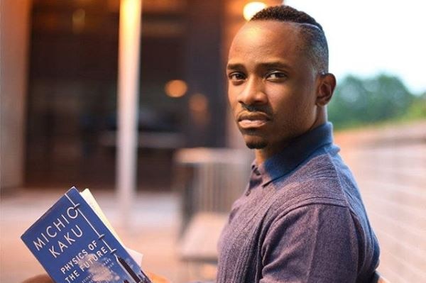New York Based tech entrepreneur Chike Ukaegbu holds a book and looks into the camera