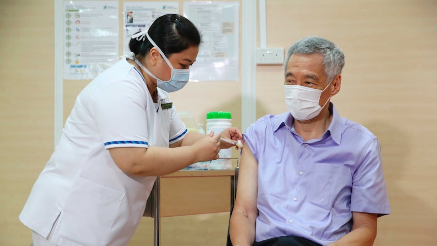 Singaporean Prime Minister Lee Hsien Loong, right, receives a vaccine for the coronavirus