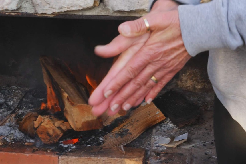 A a pair of hands rubbed together and warmed by a fireplace.