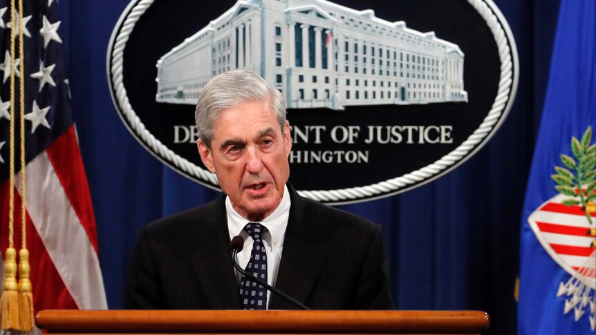 Special counsel Robert Muller wears a suit and speaks at a podium.